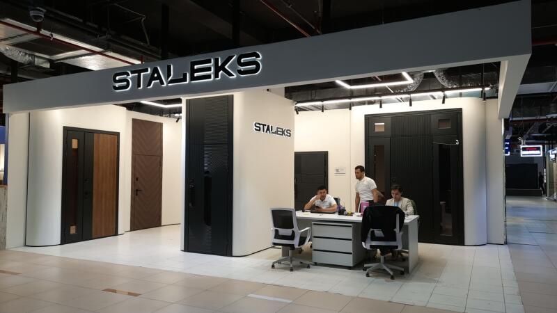The image shows a Staleks booth with several doors on display and three people inside.