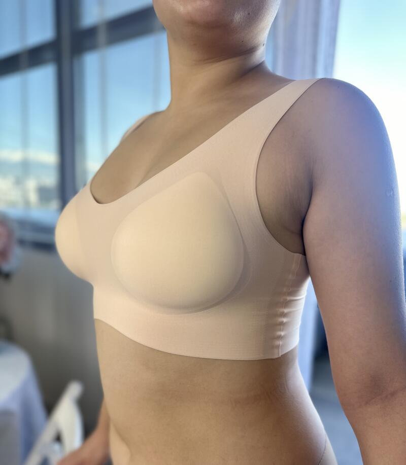 A person is wearing a nude-colored bra in a room with natural light.