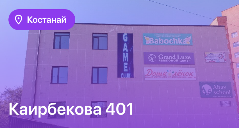 The image shows the exterior of a building in Kostanay at Kairbekova 401, featuring signs for businesses including Babochka, Grand Luxe Language Center, Doshkolenok, Abay School, and a Game Club.