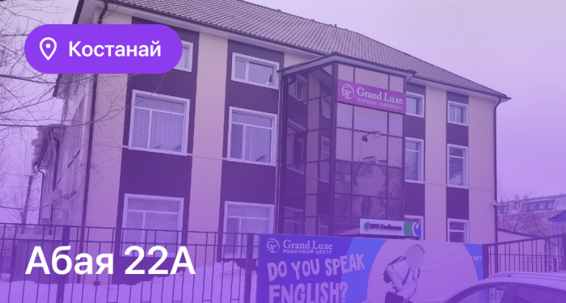 The image shows the exterior of a building with the text "Костанай" and "Абая 22А" overlaid, along with signs for "Grand Luxe ЯЗЫКОВОЙ ЦЕНТР" and the question "DO YOU SPEAK ENGLISH?".