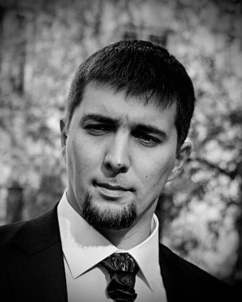 Черно-белое фото мужчины в костюме с бородкой и галстуком с узором.