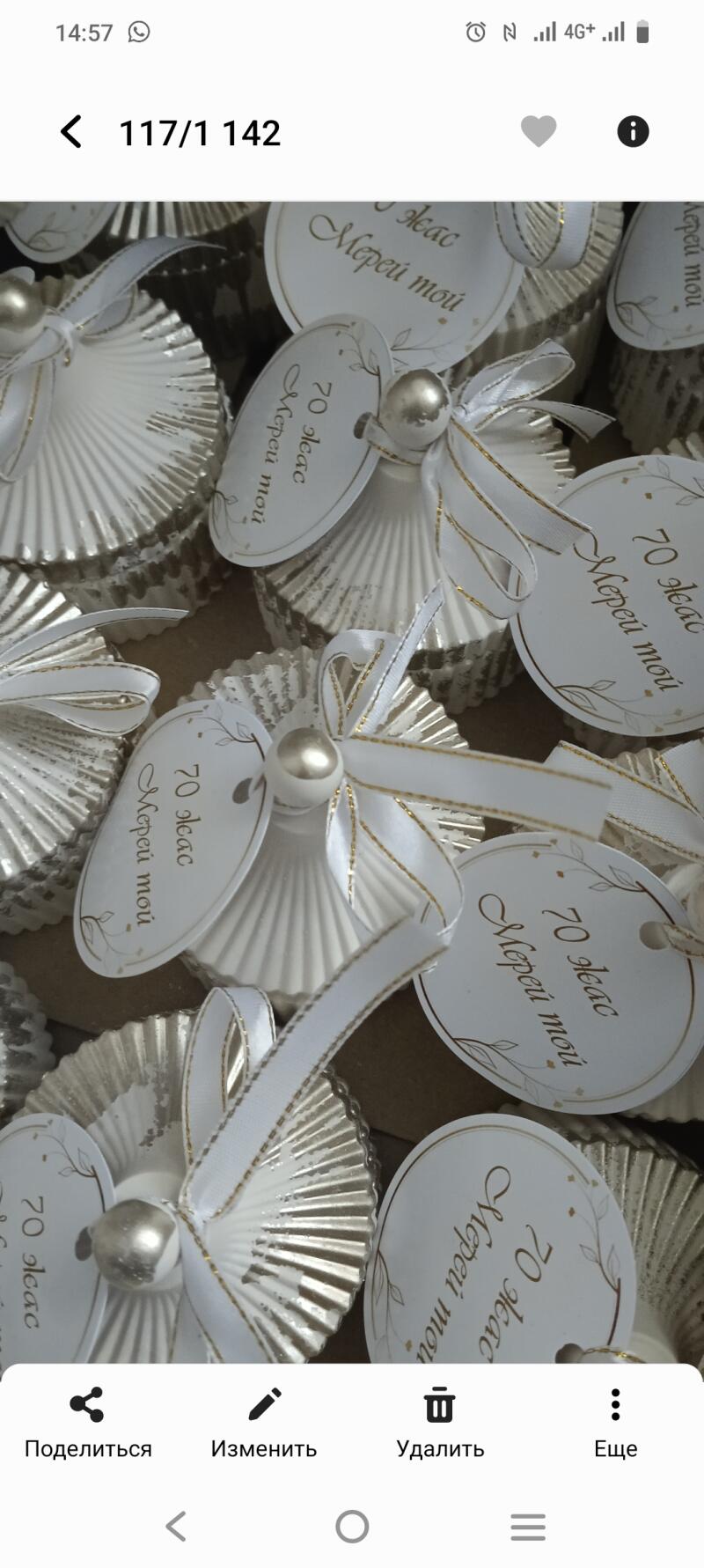 The image shows several small, decorative treats, each in a silver wrapper with a white ribbon and a tag that reads "70 жас Мерей той" in Kazakh.