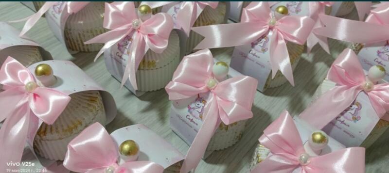 Several cupcake-shaped packages are decorated with pink bows, pearls, and golden balls, some featuring a unicorn design and the name 'Sofia'.