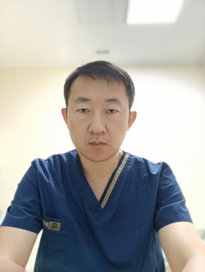 A person wearing a blue scrub top is looking directly at the camera.