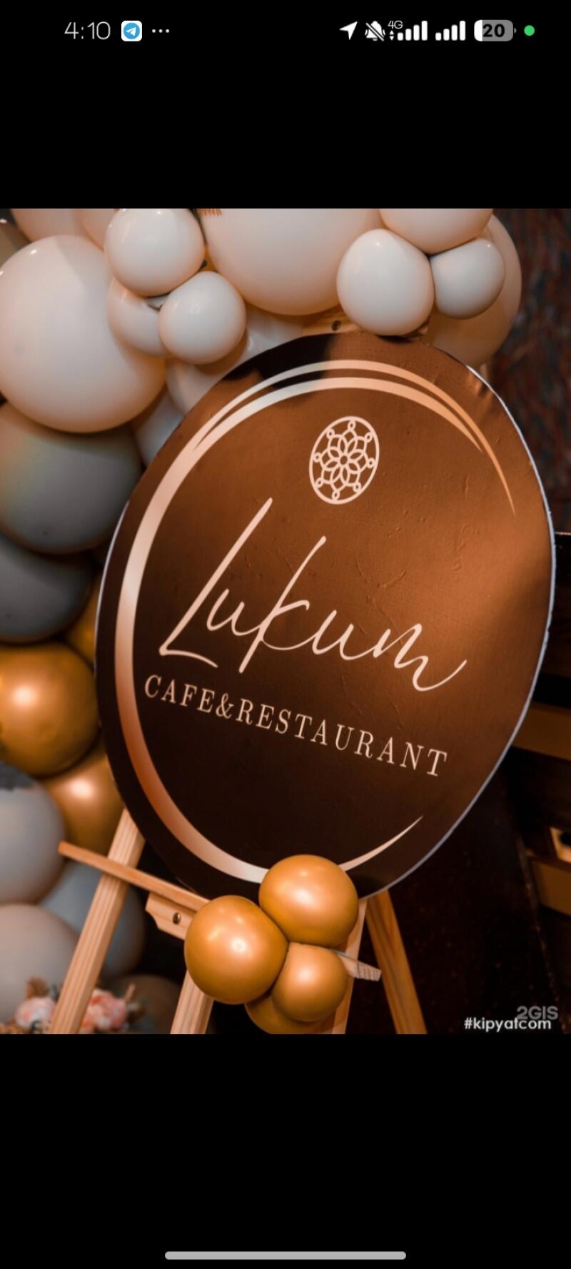 A sign for 'Lukum CAFE&RESTAURANT' is displayed on a wooden easel, surrounded by white and gold balloons.