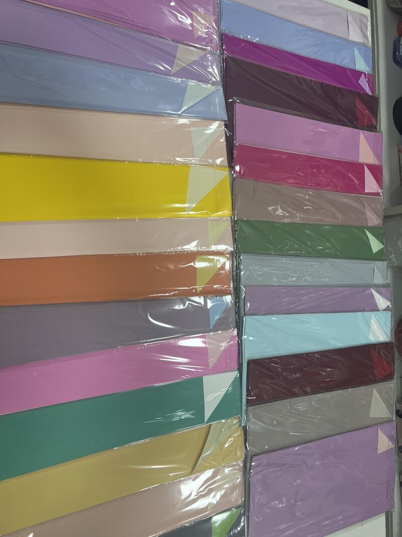 The image shows two stacks of colorful paper wrapped in plastic, with colors including purple, blue, yellow, pink, green, and brown.