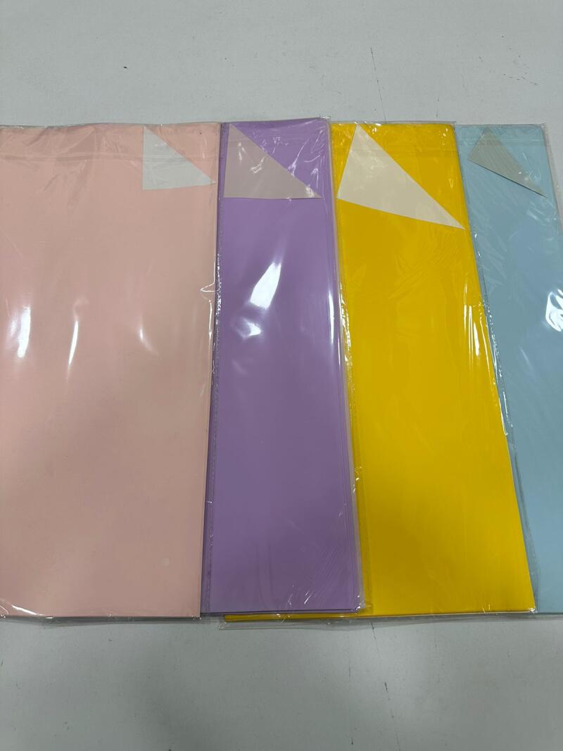 The image shows four packets of colored paper (pink, purple, yellow, and light blue) wrapped in plastic.