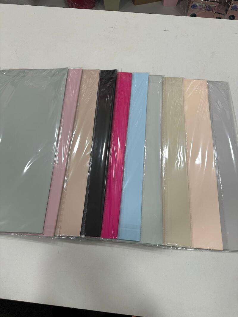 The image shows a row of colorful paper sheets, including gray, pink, beige, black, magenta, and light blue, each individually wrapped in transparent plastic.