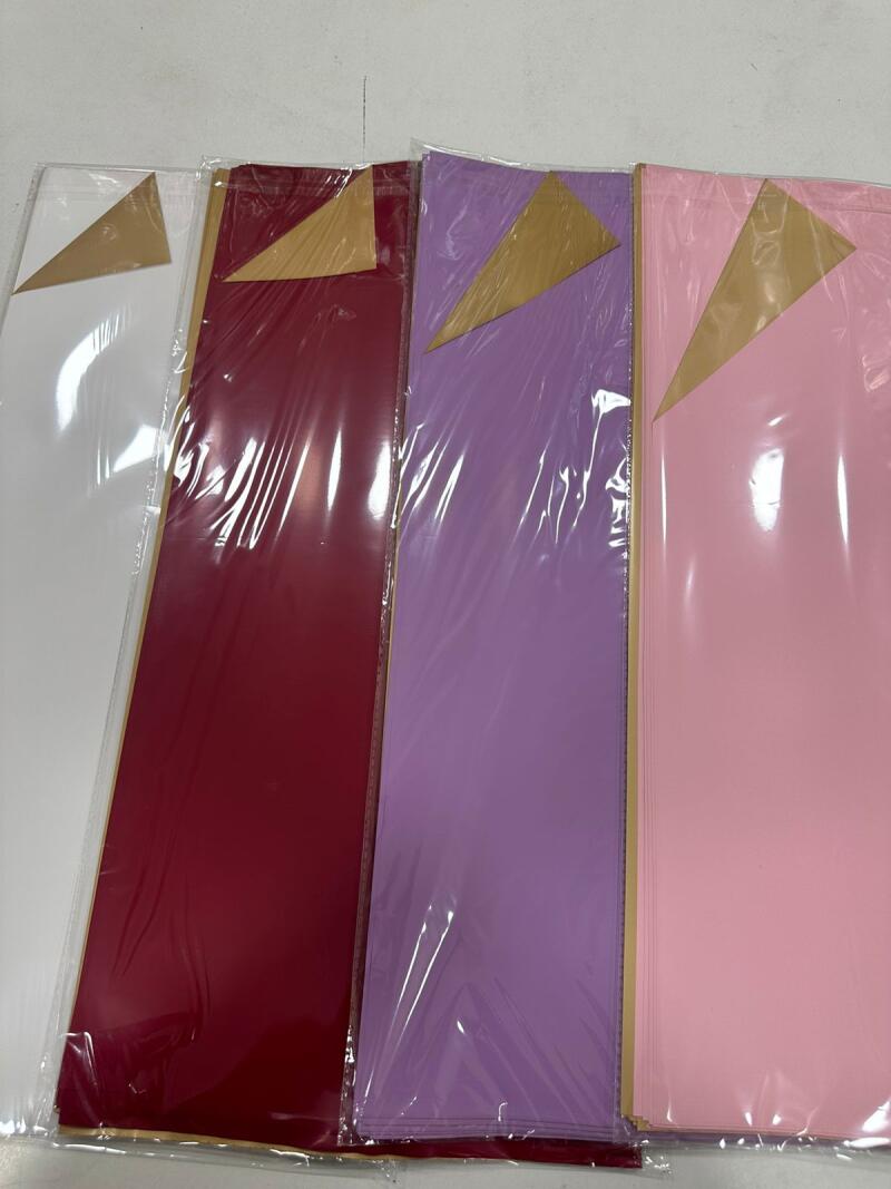 The image shows four stacks of colored paper in clear plastic packaging: white, burgundy, lavender, and pink.