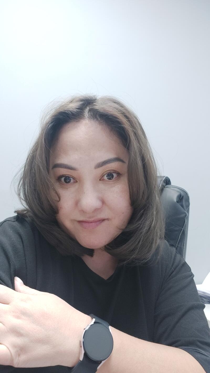 A woman with shoulder-length brown hair is wearing a black shirt and a smartwatch.