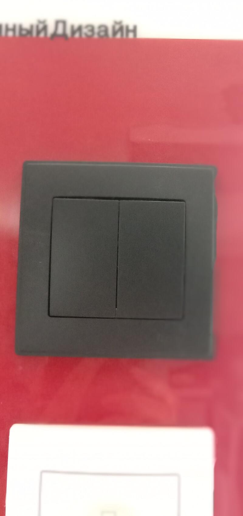 A close-up shot features a double light switch with a dark gray color, set against a background that transitions from red to white and includes some text in Russian at the top.