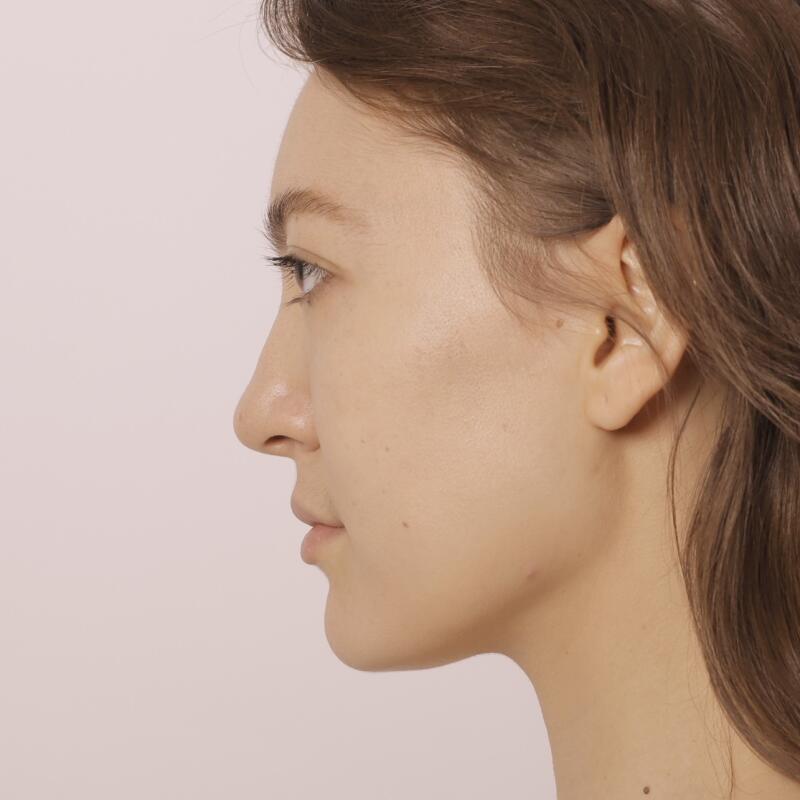 A profile view of a woman with light skin and brown hair against a light background.