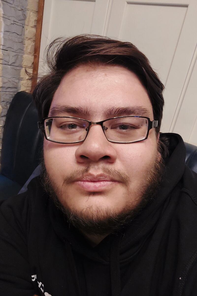 A man with glasses and a beard is wearing a black hoodie.