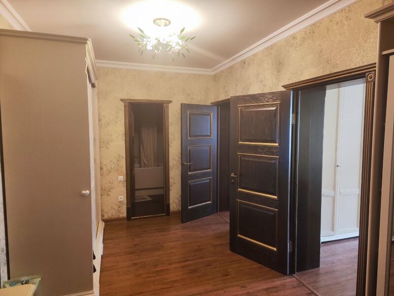 The room features patterned wallpaper, wooden floors, a decorative ceiling light, and multiple dark wood paneled doors.