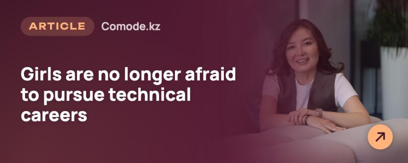 A banner featuring a smiling woman with dark hair, wearing a white t-shirt and dark vest, sitting at a table. The text "ARTICLE Comode.kz Girls are no longer afraid to pursue technical careers" is overlaid on a dark red background on the left, with an orange arrow icon in the bottom right corner.