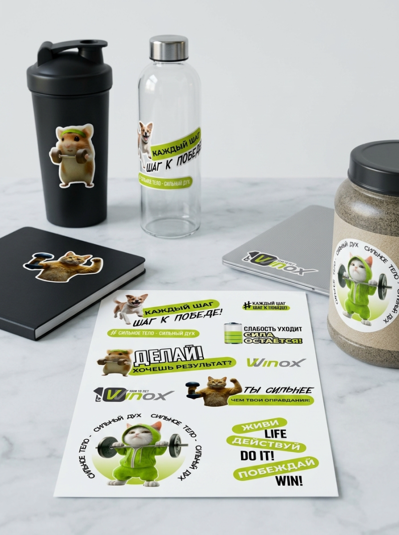 A collection of fitness-themed items on a white surface, including a black shaker, a glass water bottle, a black notebook, a silver laptop, and a jar, all adorned with stickers of animals exercising and motivational text in Russian and English, such as "КАЖДЫЙ ШАГ – ШАГ К ПОБЕДЕ!" (Every step is a step to victory!), "ДЕЛАЙ! ХОЧЕШЬ РЕЗУЛЬТАТ?" (Do it! Want a result?), "СЛАБОСТЬ УХОДИТ СИЛА ОСТАЕТСЯ!" (Weakness goes away, strength remains!), and "ЖИВИ LIFE, ДЕЙСТВУЙ DO IT!, ПОБЕЖДАЙ WIN!".
