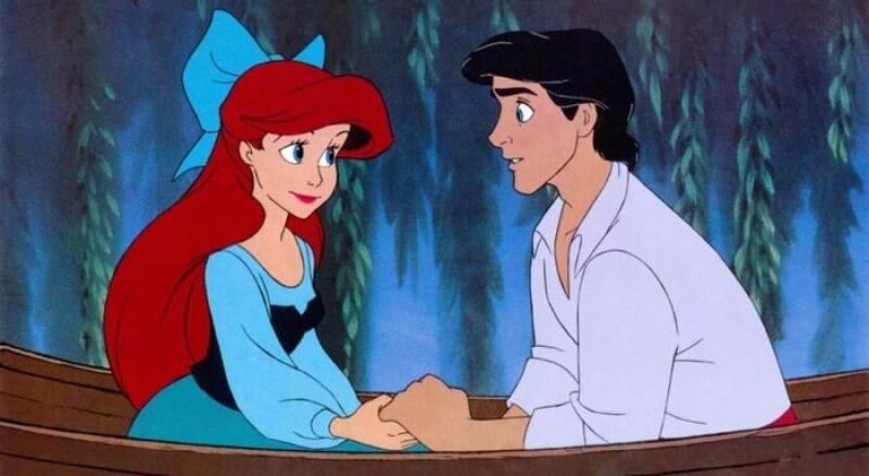 Ariel with red hair and a blue bow and Prince Eric are holding hands in a boat.