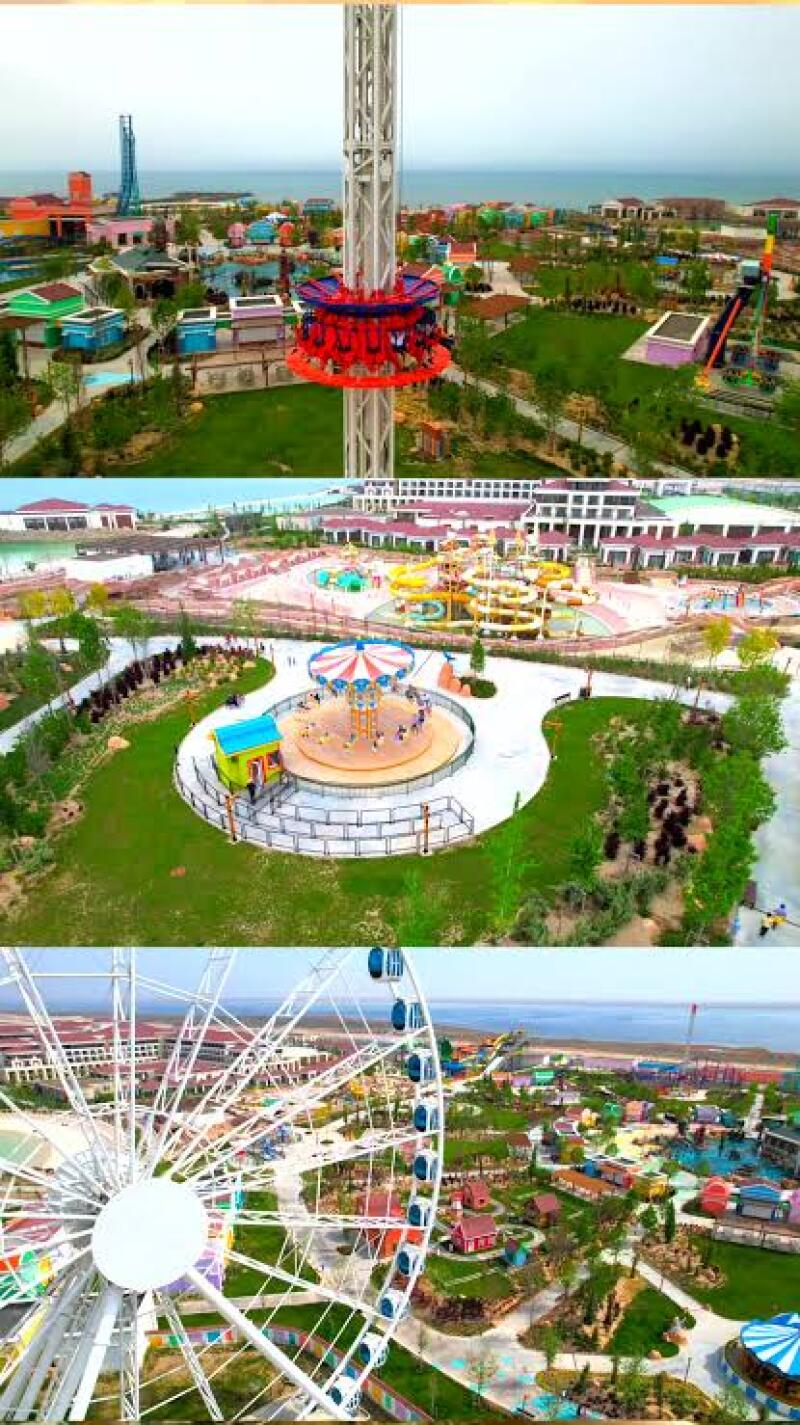 The image shows a vibrant amusement park featuring various rides, including a Ferris wheel, a drop tower, and a carousel, set against a backdrop of colorful buildings and lush greenery.