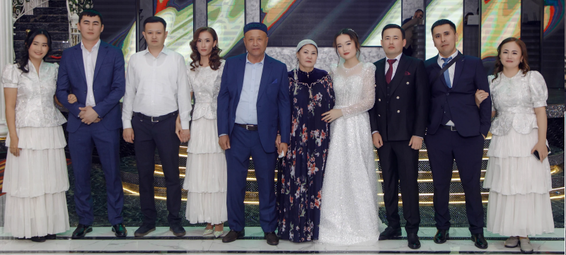 A group of ten people stand in a line, likely a family at a wedding or special event, dressed in formal wear.