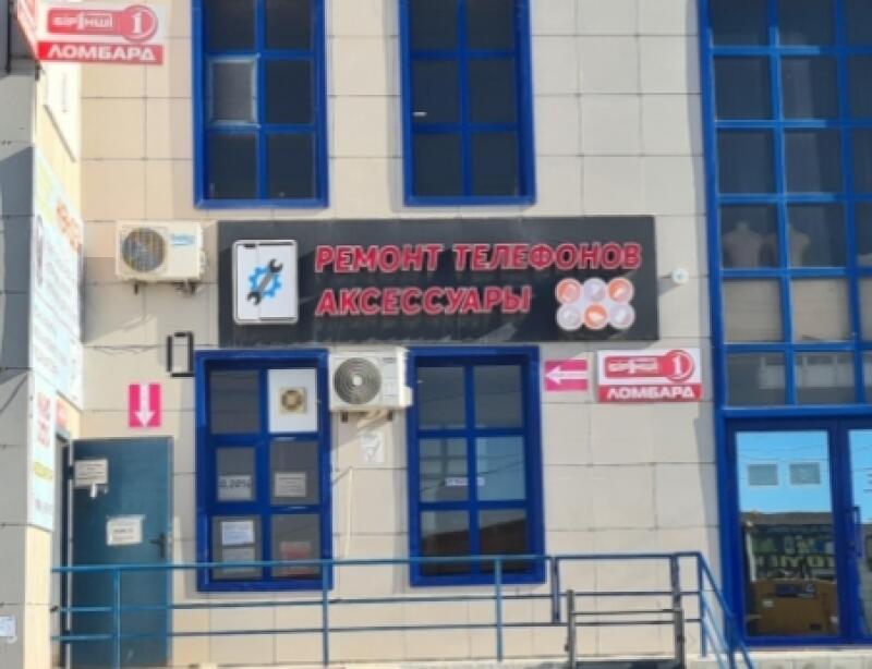 The exterior of a building with signs for 'Ремонт Телефонов Аксессуары' (Phone Repair Accessories) and 'Ломбард' (Pawnshop) is shown, featuring multiple windows with blue frames and an entrance door.