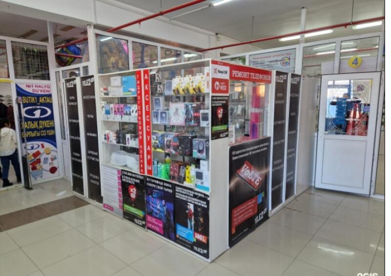 A small store in a mall selling phone accessories and offering phone repair services, with visible text including 'ACCESSORIES', 'PHONE REPAIR', 'VOLTE', and 'BUTIK1 AKTAU'.