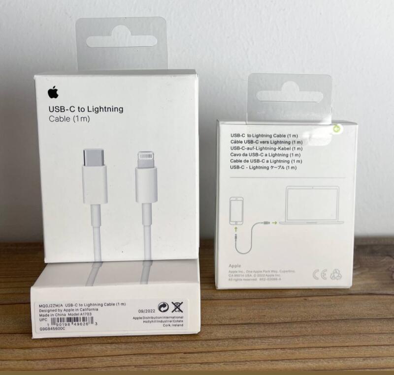 Представлены две коробки с кабелем Apple USB-C - Lightning, на одной изображен сам кабель, а на другой - схема подключения телефона к ноутбуку. На коробках текст на нескольких языках.