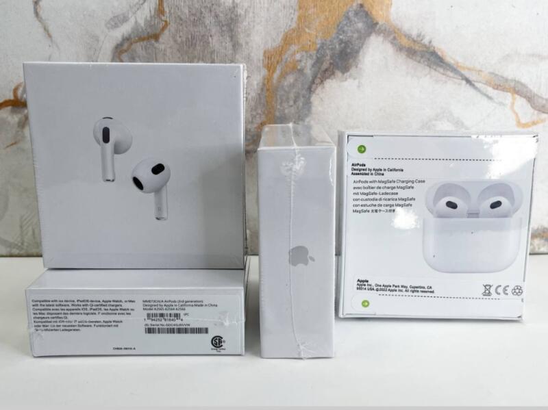 На изображении три запечатанные коробки Apple AirPods, на главной коробке изображены сами AirPods, а на других коробках - логотип Apple и информация о продукте.