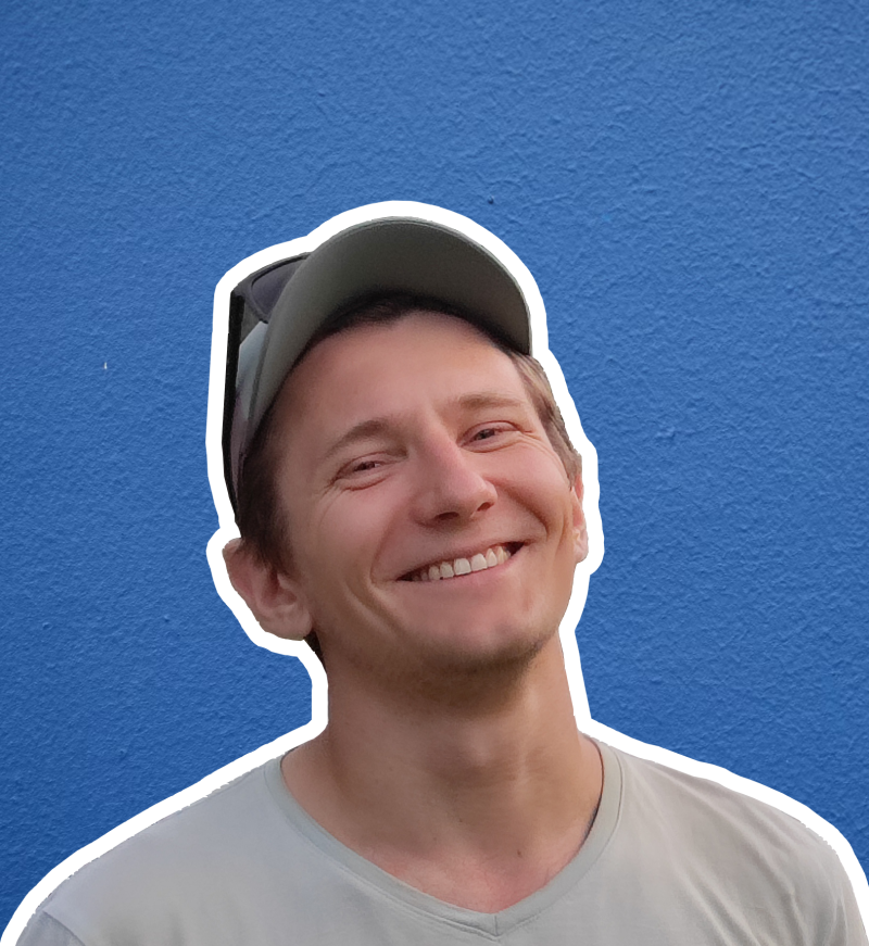 A smiling man wears a cap and a gray shirt against a blue background, outlined in white.