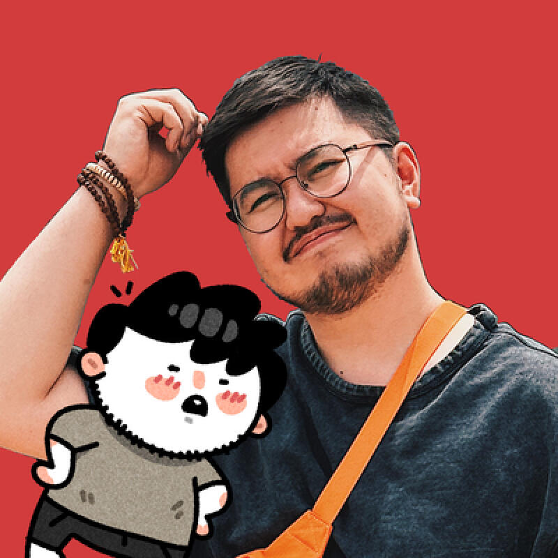 A man with glasses and a mustache poses with a cartoon character on a red background. He wears a dark gray shirt and an orange crossbody bag, while the cartoon character is depicted with rosy cheeks and a gray shirt.