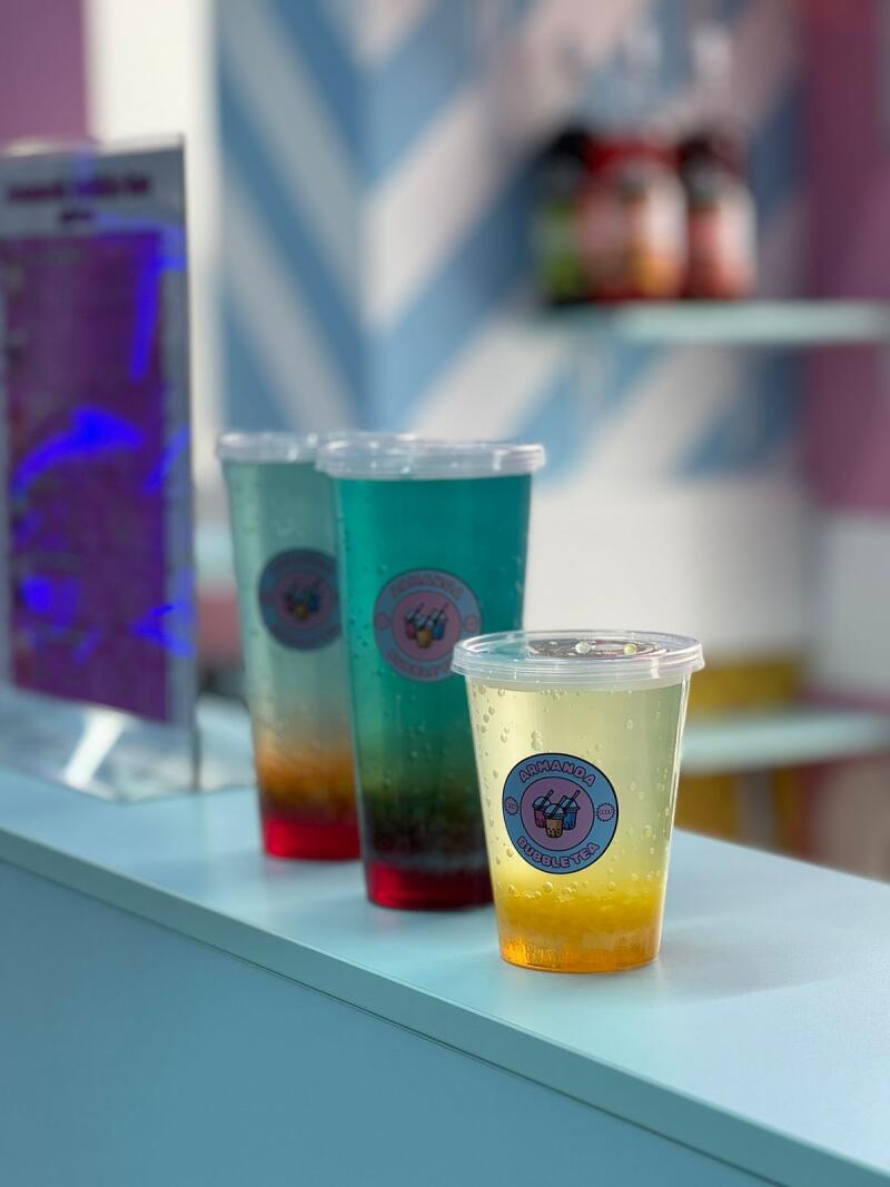 Three clear plastic cups filled with colorful bubble tea sit on a counter, each adorned with a sticker that reads "Armanda Bubble Tea".