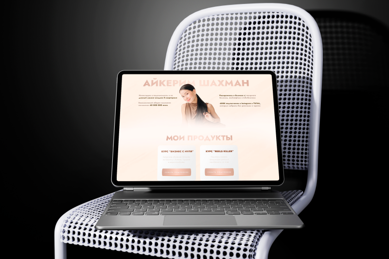 A laptop is on a white chair, displaying a webpage with the title "АЙКЕРИМ ШАХМАН" and sections for "МОИ ПРОДУКТЫ" (My Products) featuring courses like "КУРС 'БИЗНЕС С НУЛЯ'" ('BUSINESS FROM SCRATCH' COURSE) and "КУРС 'REELS KILLER'" ('REELS KILLER' COURSE).