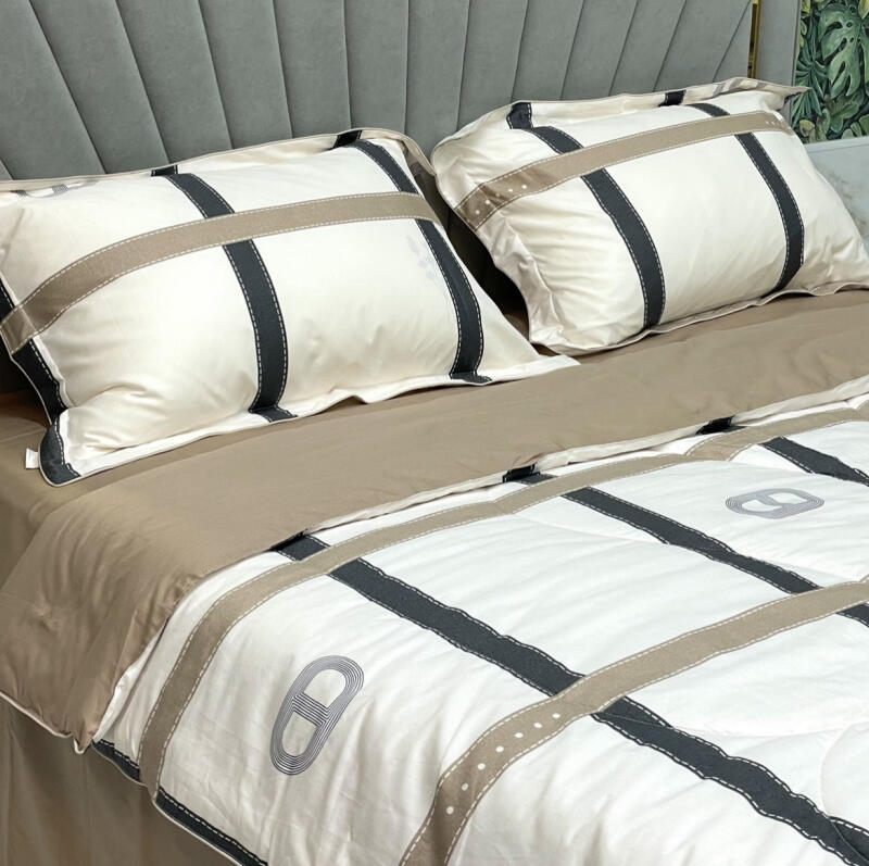 A bed is made with a white comforter and pillows that have a pattern of gray and tan stripes, along with a brown sheet underneath.