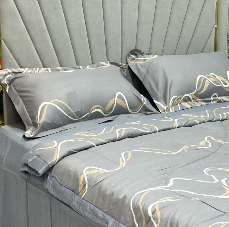 The photo shows a bed with gray linens featuring a wavy line pattern in white and gold.