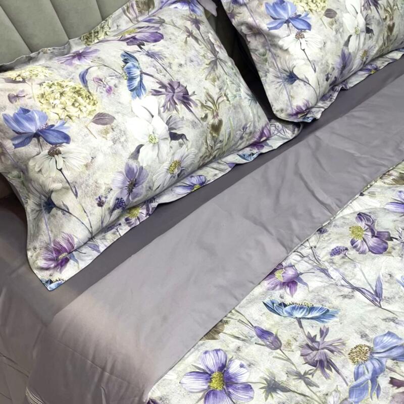 The image shows a bed with floral-patterned pillows and duvet, and a grey sheet.