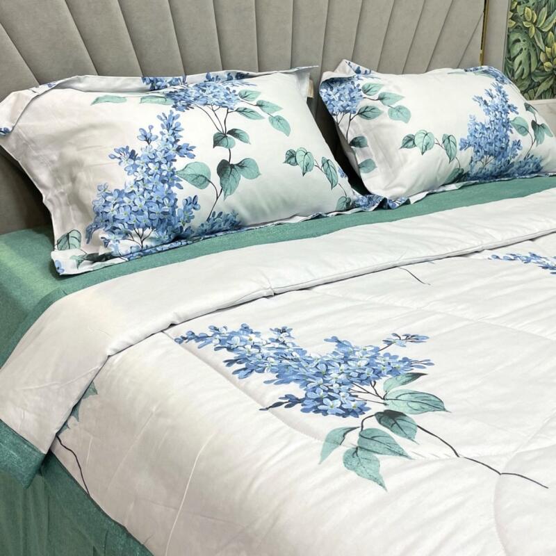 A bed with two pillows and a comforter, all decorated with blue floral patterns, sits against a gray headboard.
