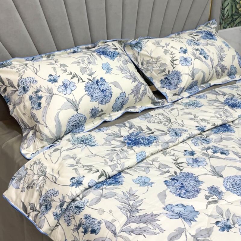 The image shows a bed with floral-patterned bedding consisting of pillows and a comforter, set against a gray headboard.