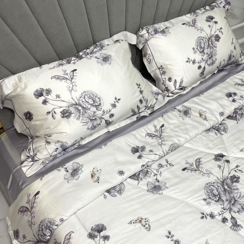 A close-up shows a bed with gray sheets and a white comforter and pillows, all adorned with a gray floral and butterfly pattern.