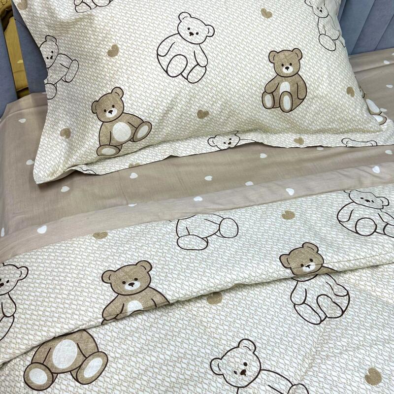 The image shows a bedding set with a teddy bear pattern in beige and white colors. The pattern consists of teddy bear figures and small heart shapes.