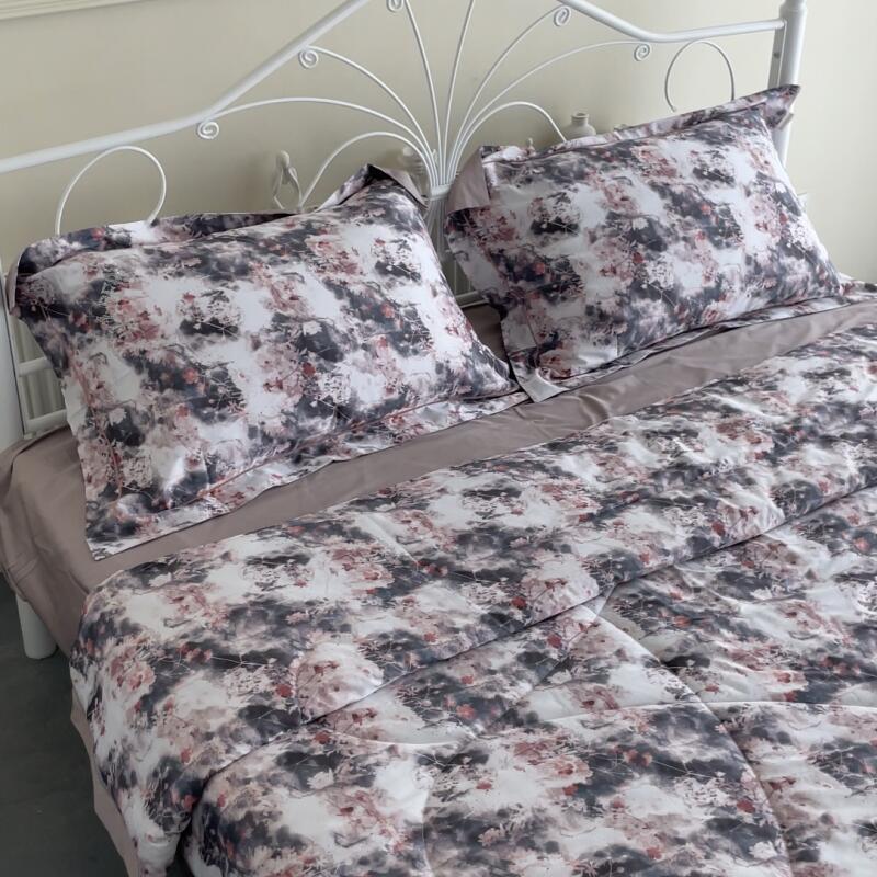 A made-up bed with a white metal frame features floral-patterned pillows and a comforter set against a beige sheet.