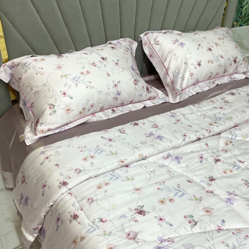 A bed is made with floral-patterned bedding, including two pillows and a comforter, set against a gray headboard.