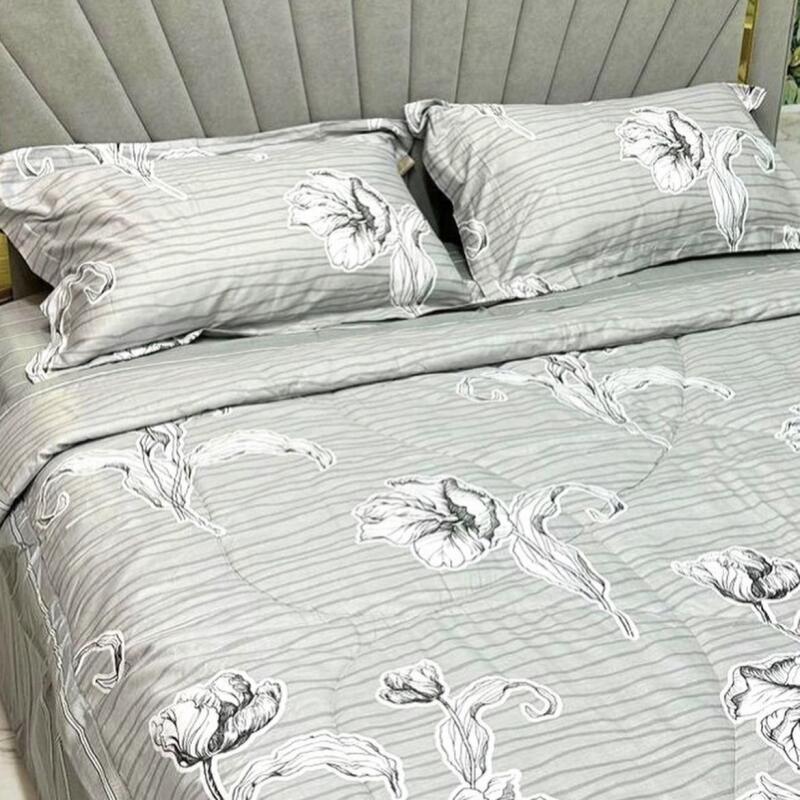 A bed is neatly made with gray floral-patterned bedding and two pillows.