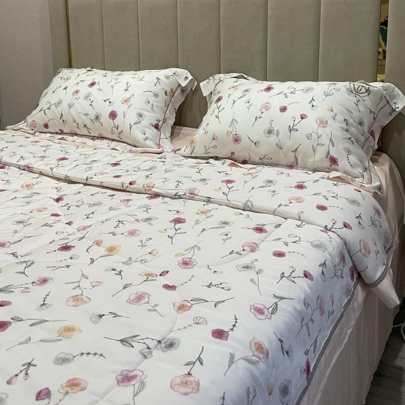A bed with two pillows and a comforter, all with a floral pattern, is neatly made.