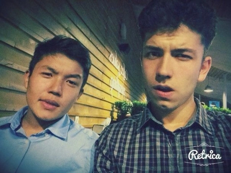 Two men pose for a selfie, one wearing a blue shirt and the other in a checkered shirt, with a "Retrica" logo in the corner.