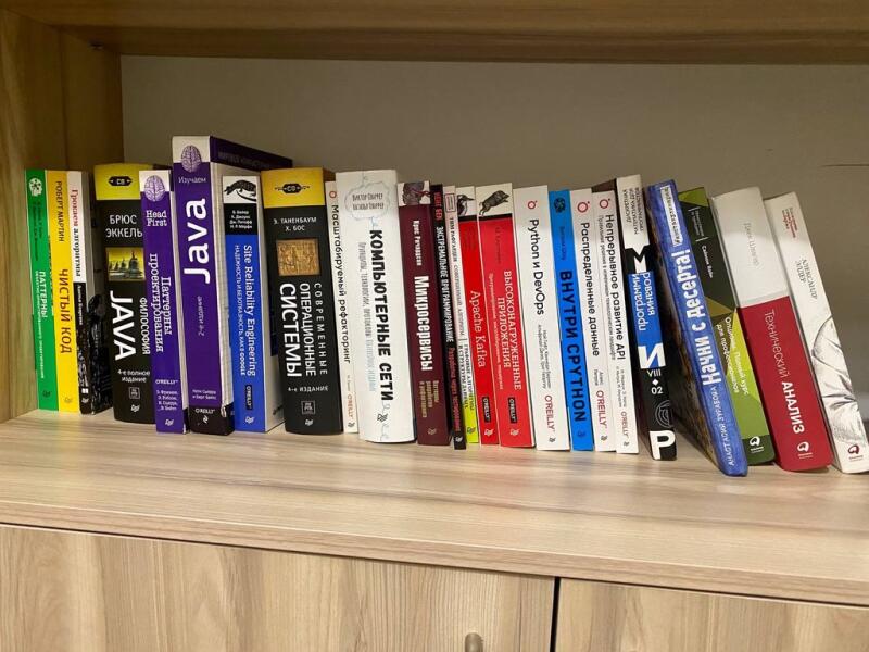 A shelf full of programming books, including titles on Java, Python, and system engineering, are displayed in a well-lit, organized manner.