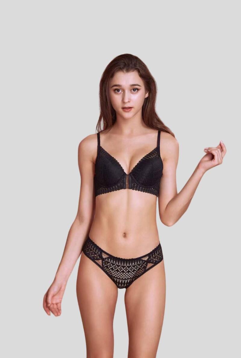 A woman with long brown hair is wearing a black bra and underwear set with lace details.