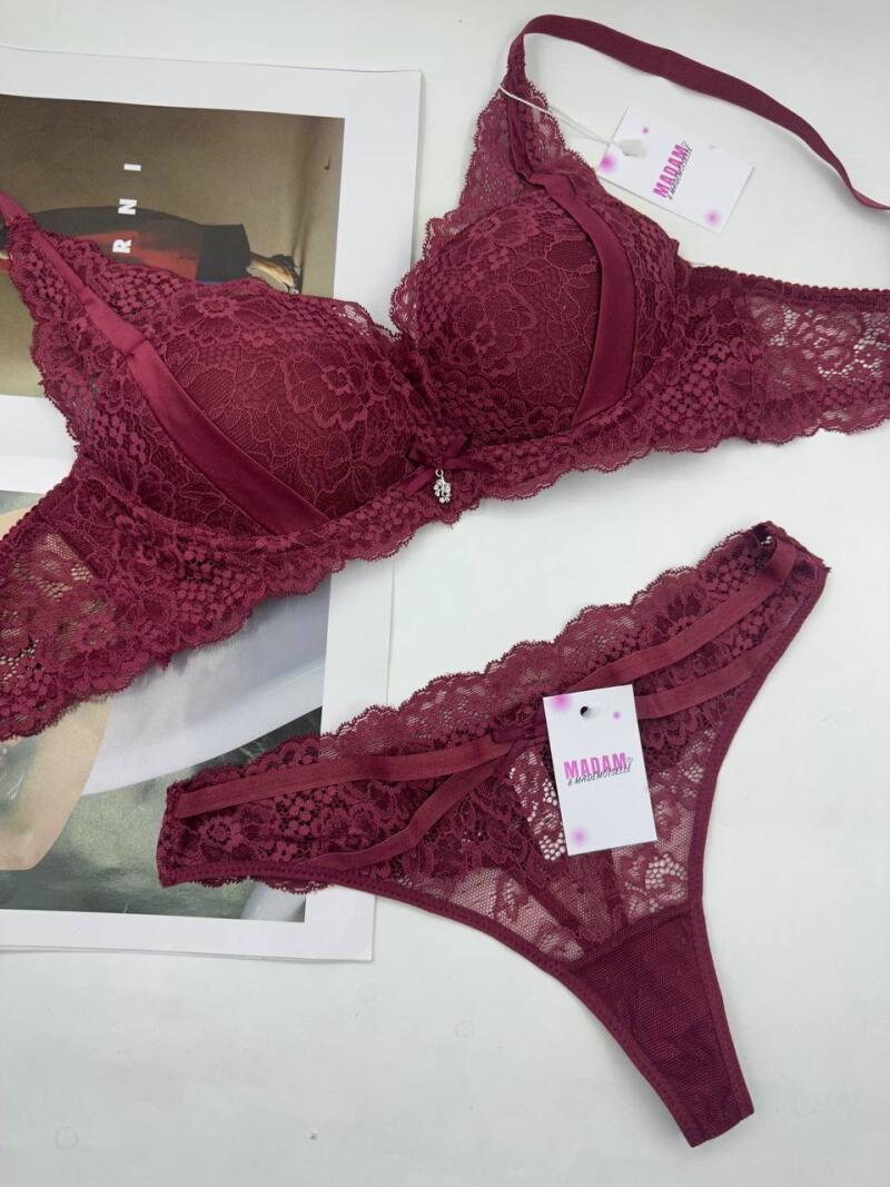 A set of burgundy lace lingerie, consisting of a bra and thong panties, is displayed with tags; the bra features a small decorative bow.
