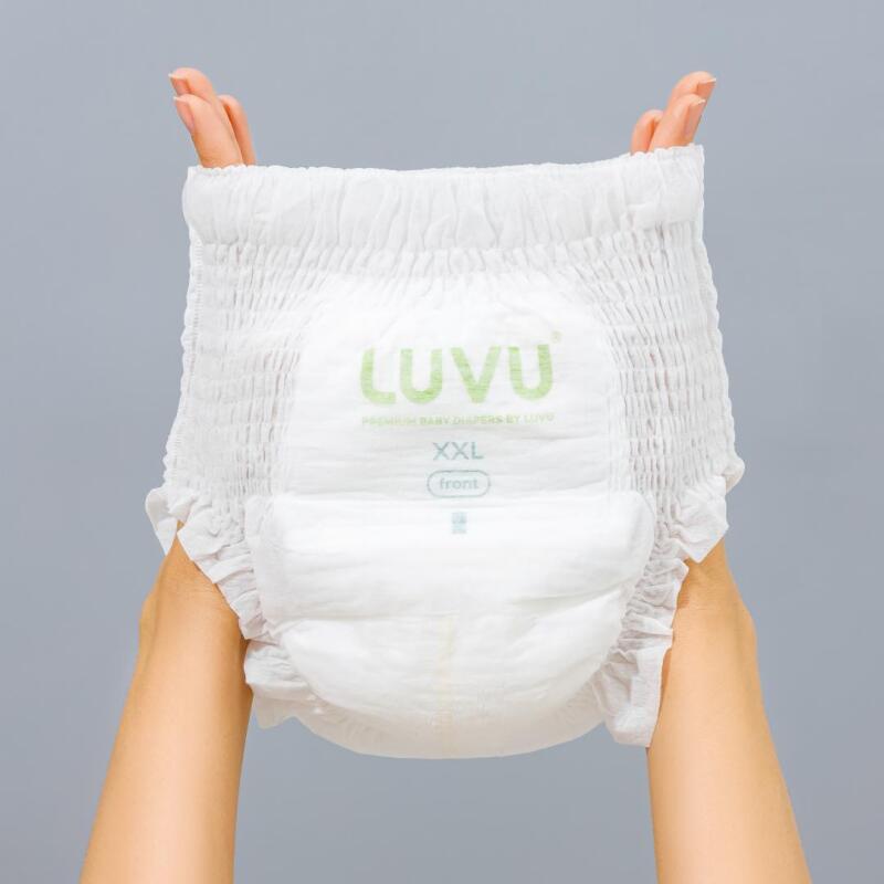 A pair of hands is holding up a white LUVU diaper, which has the brand's name printed in green, as well as the word 'front' and the size 'XXL'.