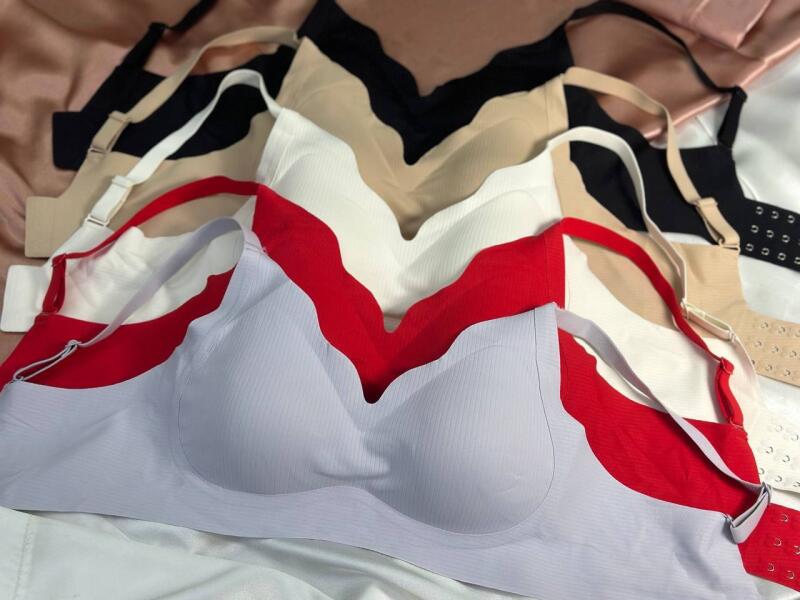 The image shows a collection of bras in various colors (gray, red, white, black, and beige) arranged on a white surface, with some showing adjustable straps and hook-and-eye closures.