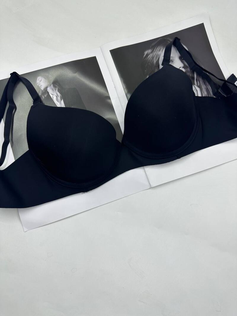 A black bra is placed on top of two black-and-white magazine pages featuring portraits of women.