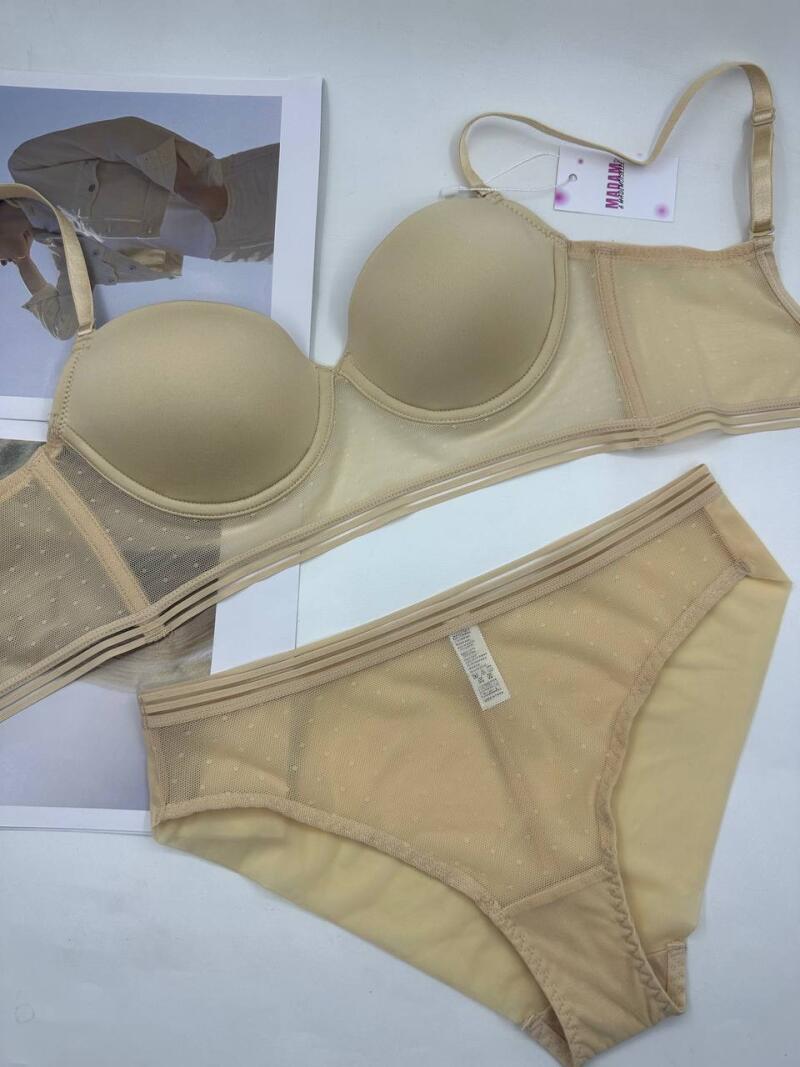 A beige-colored bra and panties set with a polka-dot pattern are displayed on a white surface, with a tag that reads 'MADAME' attached to the bra.